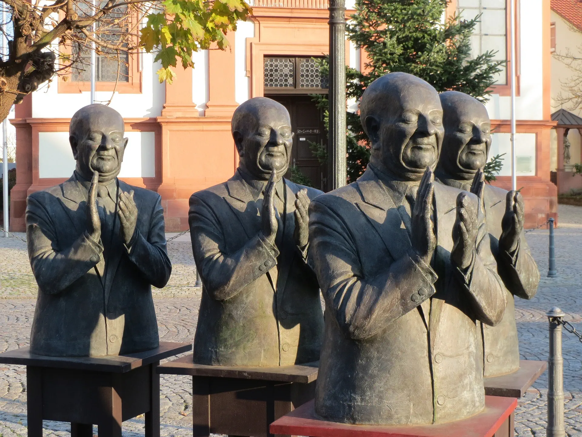 Die Abbildung zeigt die Skulpturengruppe „Die Claque“ von Guido Messer, bestehend aus vier Bronzefiguren.