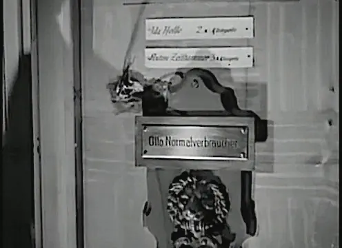 Schwarzweißaufnahme von einem Türknauf mit einem Messing-Türschild, auf dem „Otto Normalverbraucher“ zu lesen ist